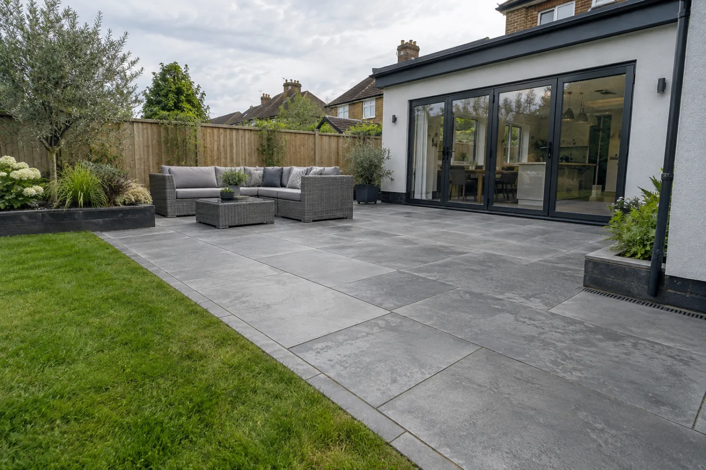 Large-format grey concrete paving beside a modest contemporary rear extension